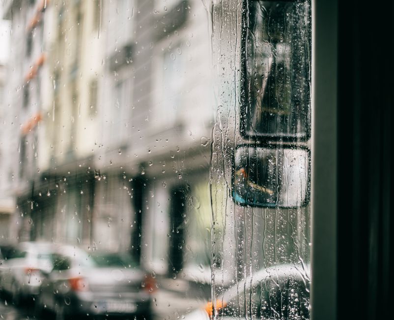 Closeup of wet glass windscreen of bus driving along city in rainy weather